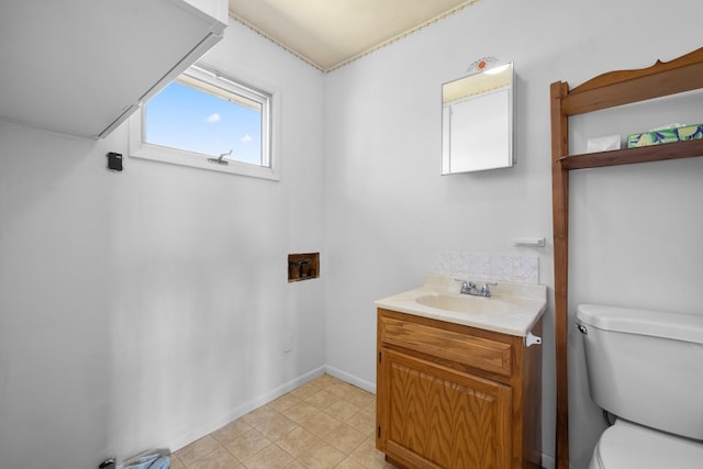 half bathroom with baseboards, toilet, and vanity