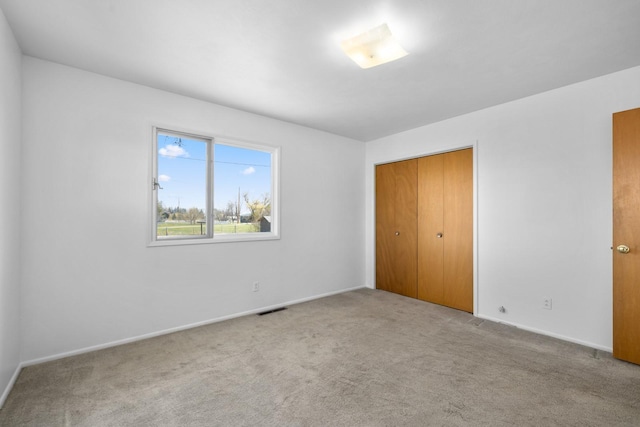 unfurnished bedroom with carpet flooring, visible vents, and baseboards