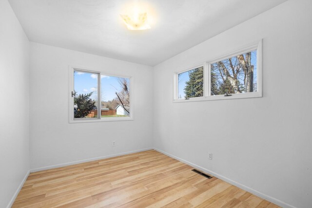 unfurnished room with baseboards, visible vents, and wood finished floors