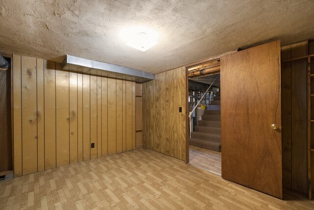 finished below grade area with wooden walls, wood finished floors, and stairs