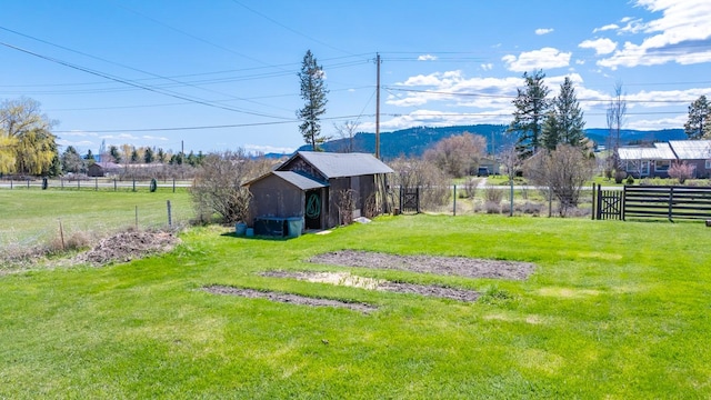 view of yard featuring an outbuilding, a mountain view, and fence