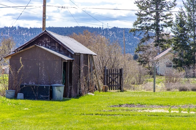 view of outdoor structure with fence, an outdoor structure, and a wooded view