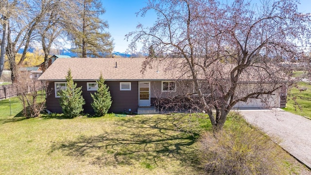ranch-style home with roof with shingles, gravel driveway, a front yard, and a garage
