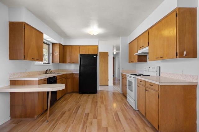 kitchen featuring light wood finished floors, a sink, under cabinet range hood, white electric range oven, and freestanding refrigerator