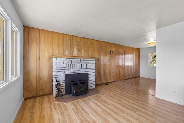 unfurnished living room with baseboards, wood finished floors, and wooden walls
