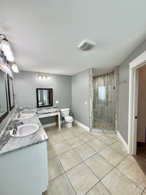 3554 Fasbender Ct, Helena, MT 59602 - full bathroom with tiled shower, toilet, tile patterned floors, and double vanity