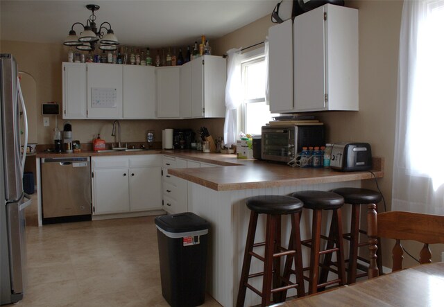 820 Lexington Ave, Butte, MT 59701 - kitchen featuring white cabinets, light countertops, freestanding refrigerator, a toaster, and a peninsula