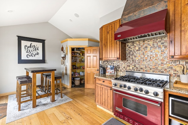 11 Wilson Butte Rd, Great Falls, MT 59405 - kitchen featuring appliances with stainless steel finishes, custom exhaust hood, tasteful backsplash, vaulted ceiling, and light wood-style flooring