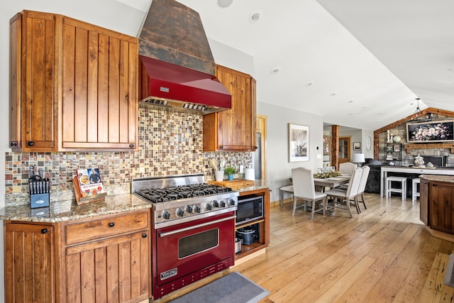 11 Wilson Butte Rd, Great Falls, MT 59405 - kitchen with stainless steel appliances, premium range hood, lofted ceiling, light stone counters, and light wood-style floors
