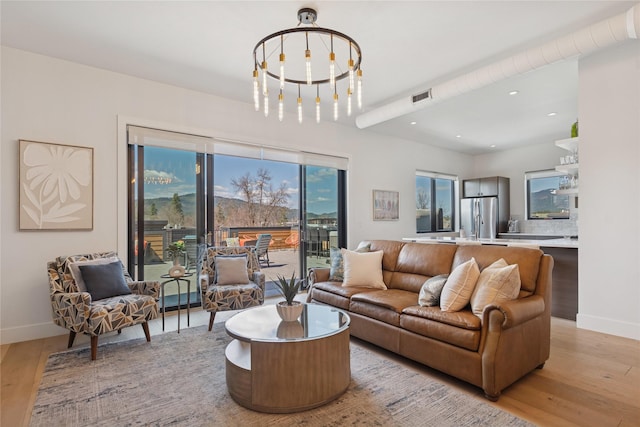 living room featuring light wood-type flooring, recessed lighting, baseboards, and a notable chandelier
