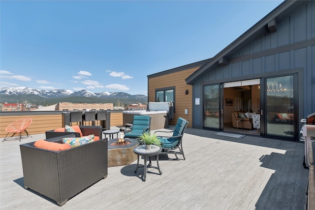 view of patio with a hot tub, a deck with mountain view, and a fire pit