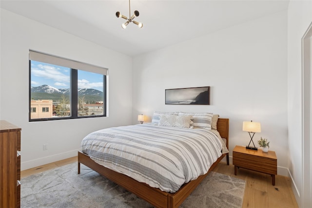 bedroom featuring baseboards, light wood-type flooring, and a notable chandelier