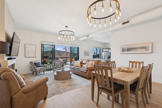 dining space with an inviting chandelier, baseboards, light wood-style floors, and visible vents