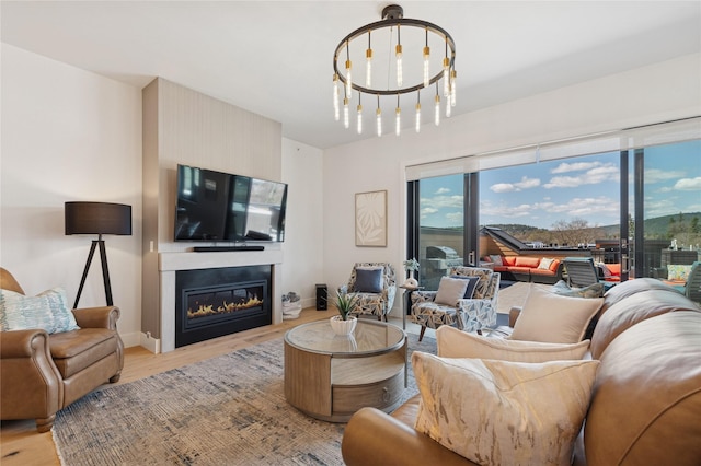 living room featuring baseboards, a glass covered fireplace, and light wood-style floors
