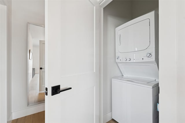 washroom featuring laundry area, stacked washer / dryer, and wood finished floors