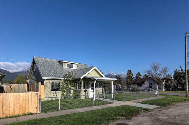 bungalow featuring a shingled roof, a fenced front yard, a gate, and a front lawn