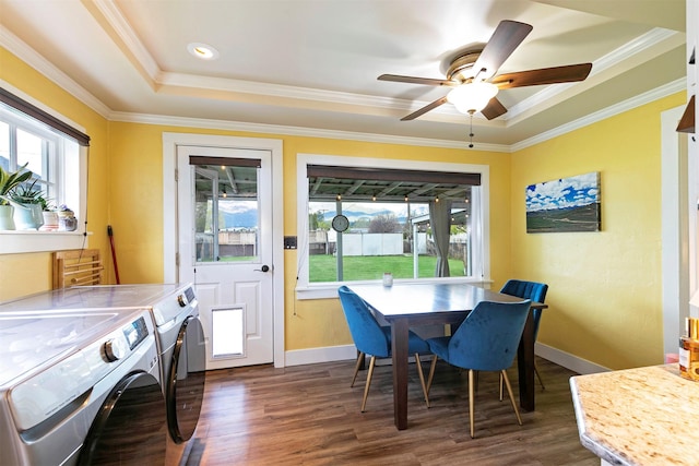 dining area featuring a raised ceiling, ornamental molding, dark wood-style floors, and washer and dryer