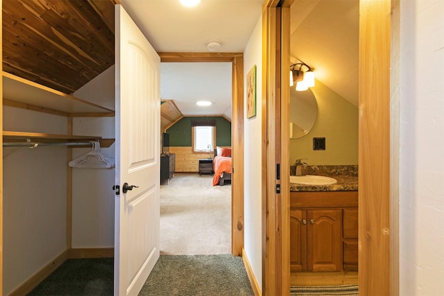 hall featuring carpet floors, a sink, and vaulted ceiling