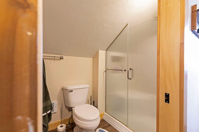 full bathroom featuring toilet, a textured ceiling, a shower stall, and lofted ceiling
