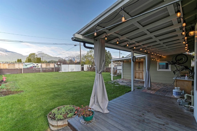 deck with a mountain view, fence, and a yard