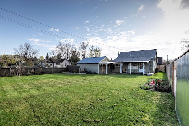 rear view of house with a porch, a fenced backyard, and a lawn
