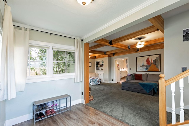 living room with ornamental molding, stairs, beam ceiling, wood finished floors, and baseboards