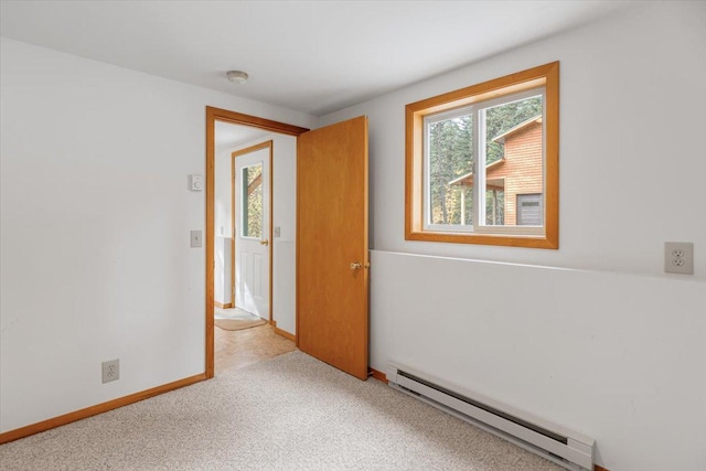 spare room featuring baseboards, a baseboard heating unit, and carpet