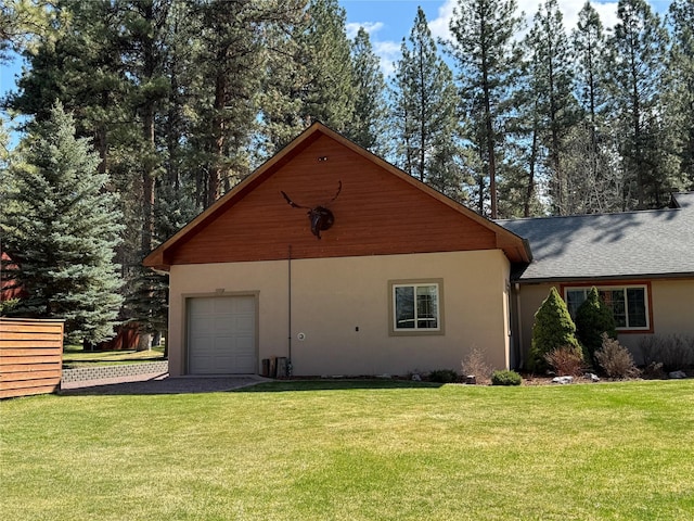 view of home's exterior featuring a garage, a yard, stucco siding, and driveway