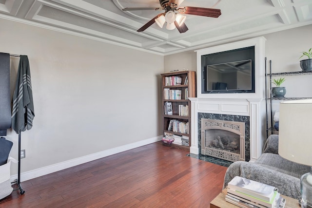 living area with wood finished floors, a fireplace, baseboards, a ceiling fan, and coffered ceiling