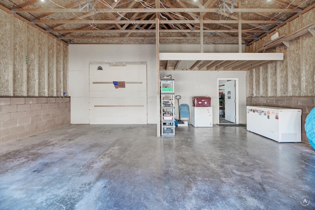 garage with concrete block wall and refrigerator