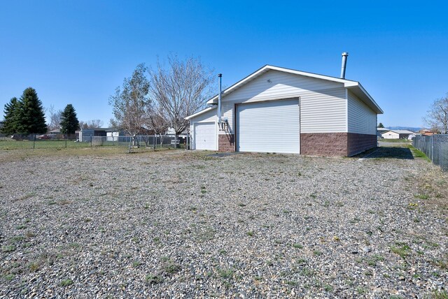 view of side of property with fence, an outbuilding, and a garage