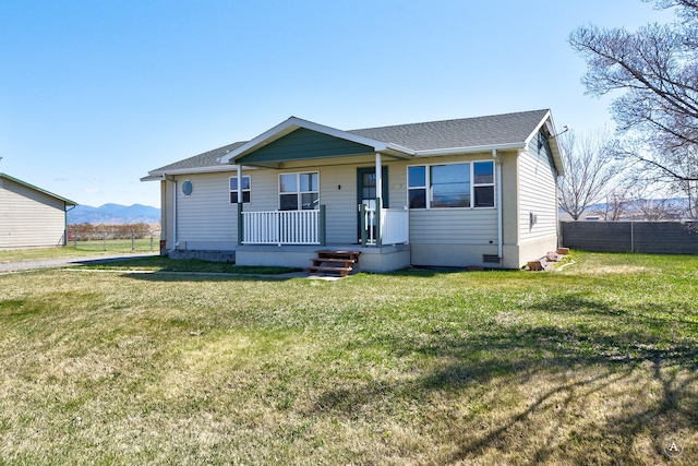 view of front of home featuring a porch, fence, a shingled roof, and a front yard