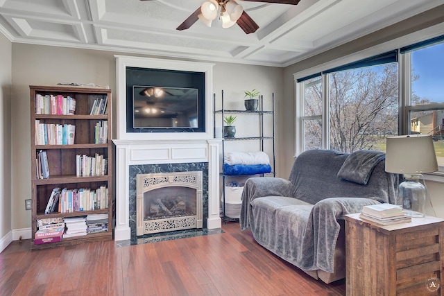 living room featuring a high end fireplace, coffered ceiling, a ceiling fan, and wood finished floors