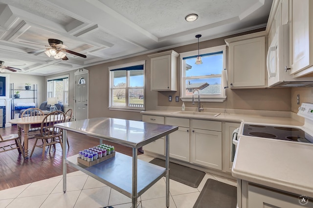 kitchen with a ceiling fan, pendant lighting, a sink, light countertops, and light tile patterned floors