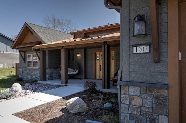 1207 Creek Crossing Rd, Missoula, MT 59802 - view of exterior entry with a porch, a shingled roof, and stone siding