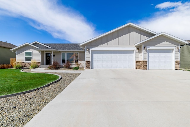 view of front of house featuring board and batten siding, a front yard, concrete driveway, an attached garage, and stone siding