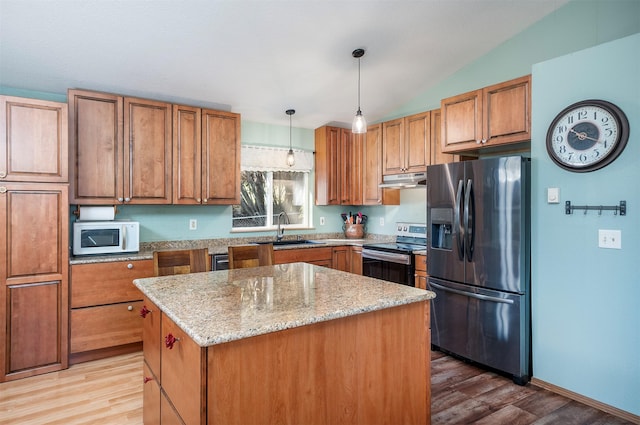 103 Tamarack Woods Dr, Lakeside, MT 59922 - kitchen with a center island, light stone counters, a sink, light wood finished floors, and appliances with stainless steel finishes