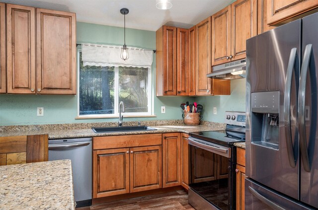103 Tamarack Woods Dr, Lakeside, MT 59922 - kitchen featuring under cabinet range hood, brown cabinets, a sink, appliances with stainless steel finishes, and hanging light fixtures