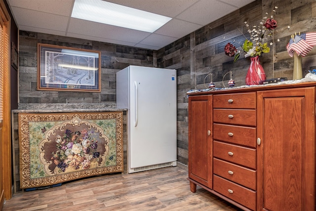 103 Tamarack Woods Dr, Lakeside, MT 59922 - kitchen featuring light wood-type flooring, freestanding refrigerator, a drop ceiling, and wooden walls