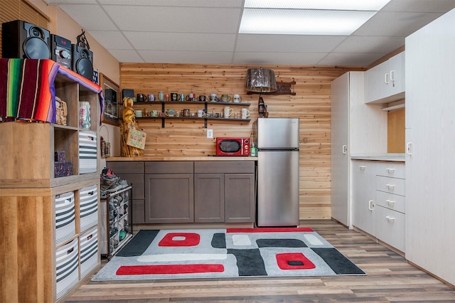 103 Tamarack Woods Dr, Lakeside, MT 59922 - kitchen with open shelves, freestanding refrigerator, wooden walls, and light wood-type flooring