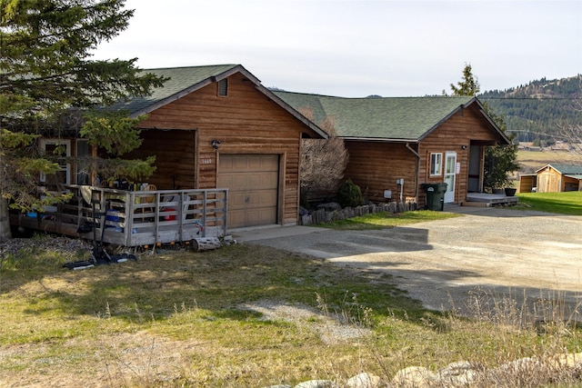 log-style house with dirt driveway and a shingled roof