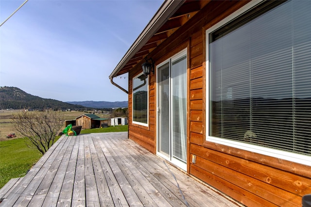 deck featuring a storage unit, a mountain view, and an outdoor structure