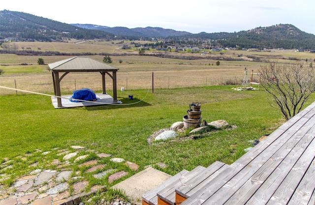 view of yard featuring fence, a mountain view, a gazebo, and a rural view