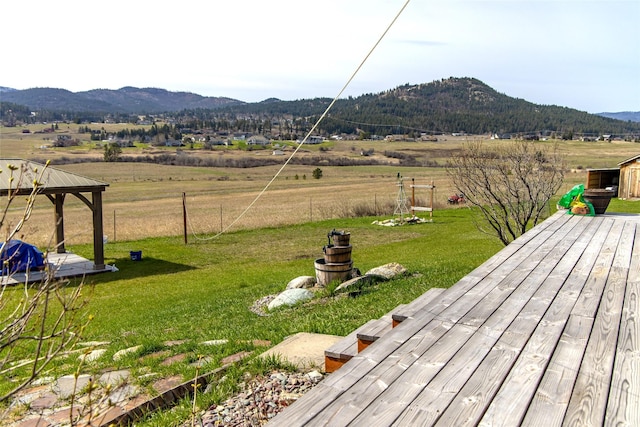 view of yard featuring a deck with mountain view, a gazebo, fence, and a rural view