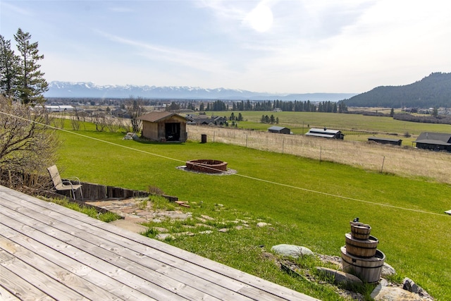 view of yard with fence, a storage unit, an outbuilding, a mountain view, and a fire pit