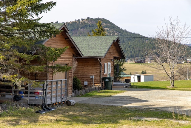 view of property exterior with a mountain view and a shingled roof