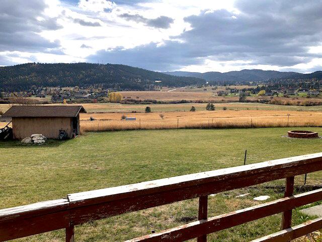 view of yard with fence, a shed, a rural view, a mountain view, and an outbuilding