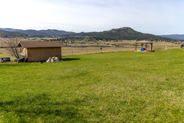 view of yard with fence, a storage unit, a mountain view, and a gazebo