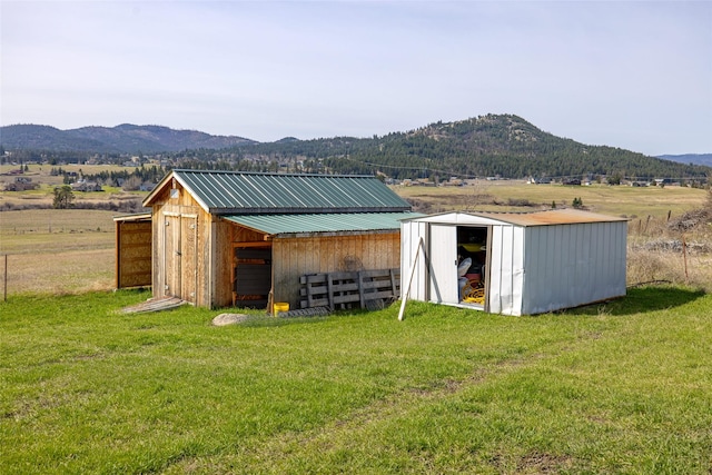 view of pole building featuring a lawn, a mountain view, and a rural view
