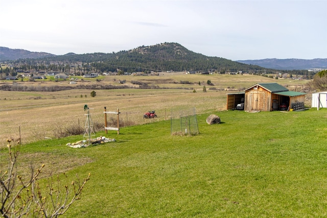 view of yard featuring an outdoor structure, a rural view, a pole building, and a mountain view